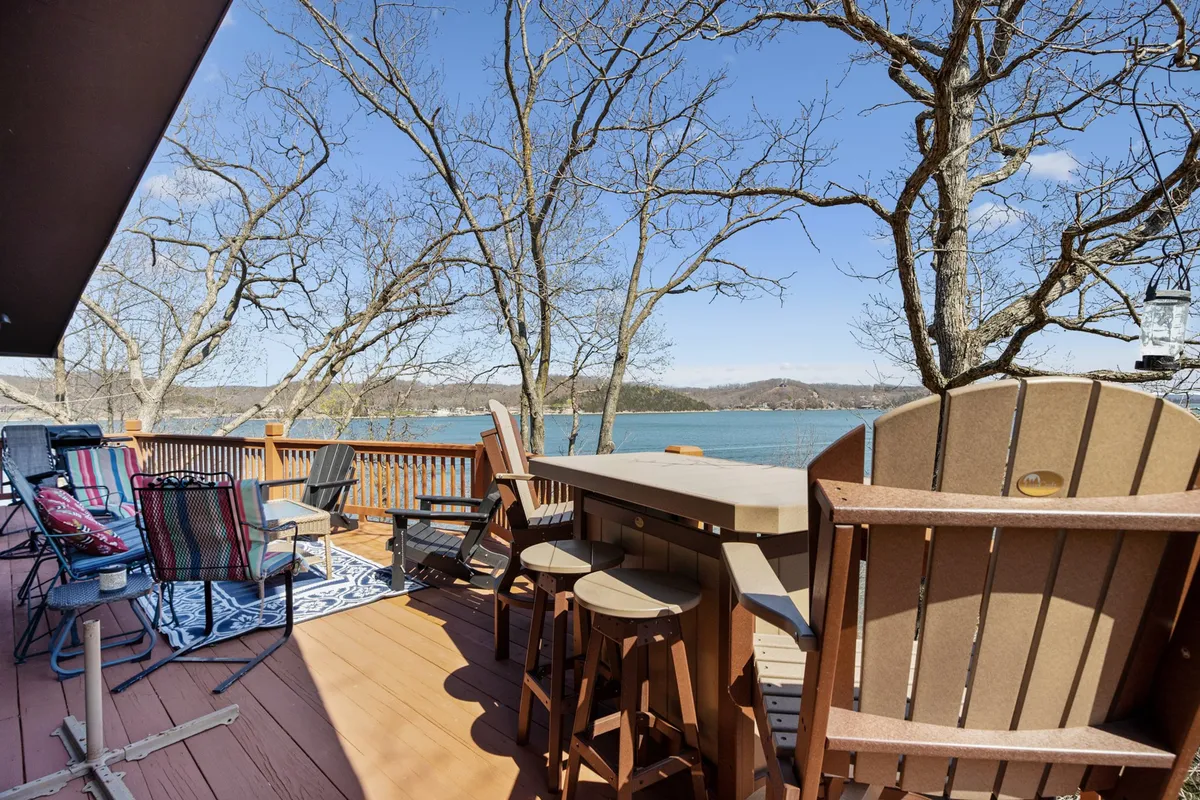 An inviting lake-view deck with comfortable furniture and a bar area, ideal for outdoor dining, relaxing with family, and enjoying scenic views of the main channel.