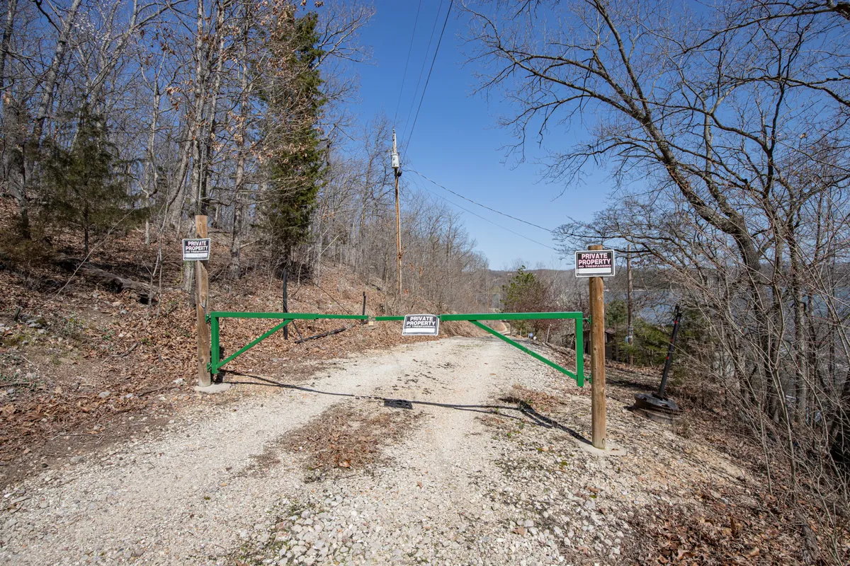 An exterior view featuring a secure gate along a quiet roadway, surrounded by trees and nature. The gate stands as a clear barrier to entry and signals enhanced security and privacy for all guests.